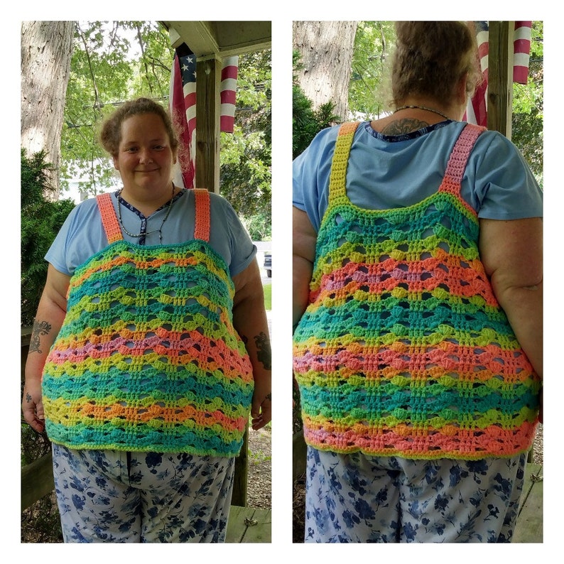 May include: A rainbow crochet top with a wide, open neckline and a loose, flowy fit. The top is made with a colorful yarn that creates a striped pattern. The top is worn over a blue shirt and floral pants.