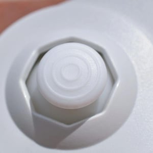 Könnte beinhalten: Nahaufnahme eines weißen Knopfes mit einem kreisförmigen Muster auf einem weißen Gamecontroller.
