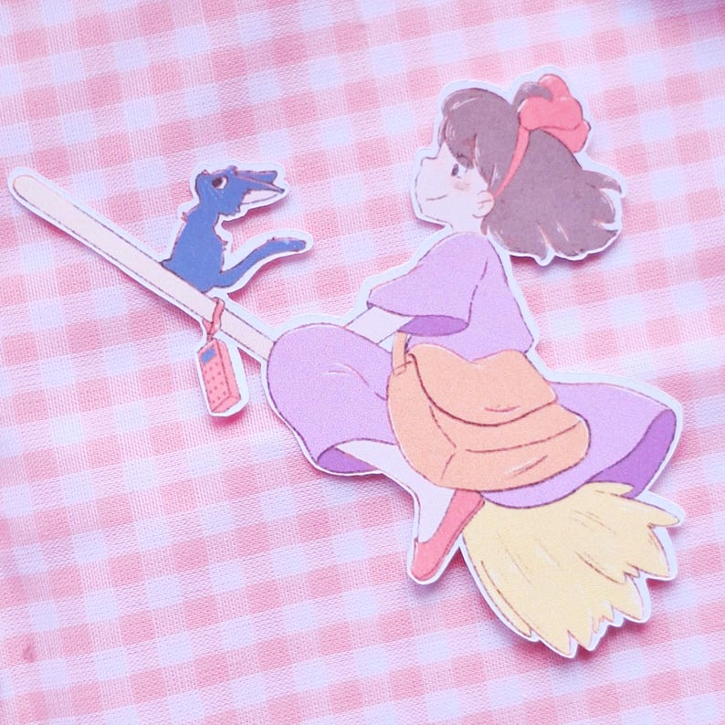 May include: A charming illustration of a girl on a broomstick with a blue companion. She wears a purple dress and a red bow. A tan satchel is slung over her shoulder. The broom has a yellow straw end and a small phone.
