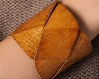May include: A brown leather cuff bracelet with a woven design.