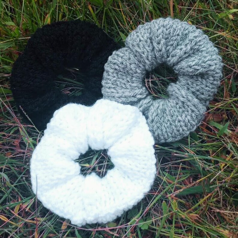 Pu&ograve; includere: Tre scrunchies per capelli in maglia nera, bianca e grigia. Gli scrunchies sono realizzati con un filato morbido e testurizzato.