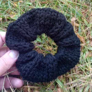 Pu&ograve; includere: Un elastico per capelli in crochet nero. L'elastico &egrave; realizzato con un filato spesso e morbido e ha un design semplice e classico.