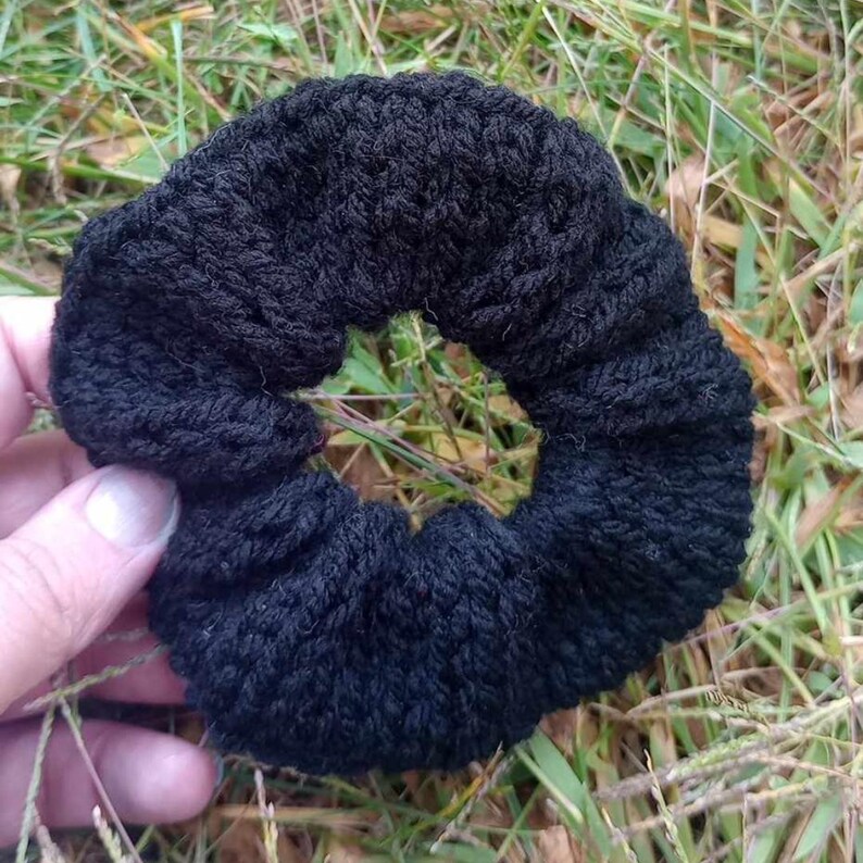 Pu&ograve; includere: Un elastico per capelli in crochet nero. L'elastico &egrave; realizzato con un filato spesso e morbido e ha un design semplice e classico.