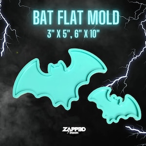 May include: Two silicone molds shaped like bats. The larger mold is 6 inches by 10 inches and the smaller mold is 3 inches by 5 inches. The molds are a light turquoise color.