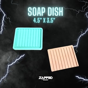Puede incluir: Dos jaboneras de silicona, una azul claro y otra marr&oacute;n claro, con un dise&ntilde;o acanalado. Las jaboneras miden 4,5 pulgadas por 3,5 pulgadas. "SOAP DISH 4.5" X 3.5" ZAPPED3D DESIGN" est&aacute; escrito en blanco sobre fondo negro.