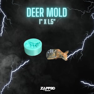 May include: A teal silicone mold for making deer figurines. The mold is 1 inch by 1.5 inches. A small brown and white deer figurine is shown next to the mold.