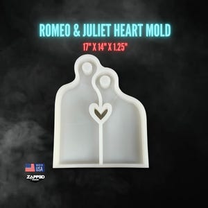 May include: A white silicone mold in the shape of two figures embracing, with a heart-shaped space between them. The text "ROMEO & JULIET HEART MOLD" is above the mold, with dimensions of 17" x 14" x 1.25". The mold is made in the USA.