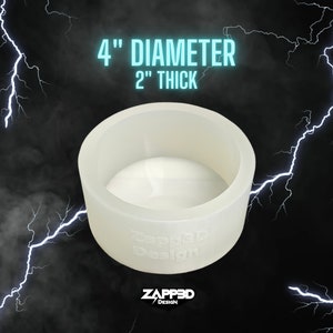 May include: A white, 4 inch diameter, 2 inch thick, round silicone mold. The mold is made by Zapped3D Design.