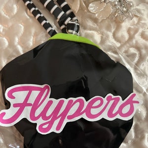 Könnte beinhalten: Schwarze und grüne Schwimmflossen mit einem weiß-schwarz gestreiften Band. Die Flossen haben ein pinkfarbenes Logo mit der Aufschrift "Flypers".