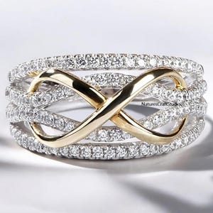 May include: A gold and silver infinity ring with a band of small clear stones. The infinity symbol is made of gold and is surrounded by a band of silver with clear stones.