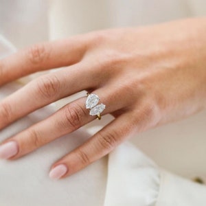 K&ouml;nnte beinhalten: Ein goldener Ring mit drei birnenf&ouml;rmigen Diamanten, die in einem zarten, geschwungenen Design gefasst sind.