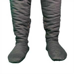 Lower section of black quilted leg wraps and attached feet, showing metal eyelets and laces.