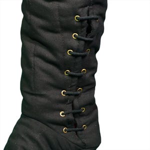 Close-up of black quilted fabric showing vertical stitching and metal grommets with a dark cord lace.