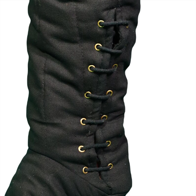 Close-up of black quilted fabric showing vertical stitching and metal grommets with a dark cord lace.