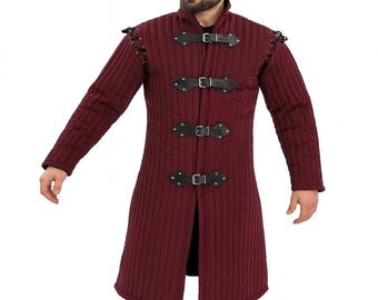 May include: A burgundy quilted coat with black leather straps and buckles. The long-sleeved coat has a high collar and is fastened with three buckles down the front. The shoulders have decorative leather accents.