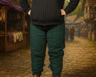 May include: Green quilted leg armor with tie closures, worn with brown leather boots. The armor is part of a medieval costume, designed for historical reenactments or theatrical performances. The quilted design provides padding and protection.