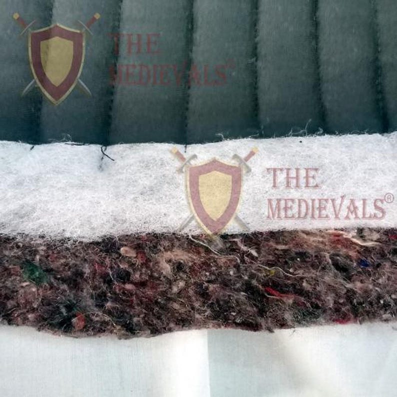 A close-up cross-section view showing the layers of quilted fabric material, including dark green fabric, white batting, and a thick speckled inner padding layer.