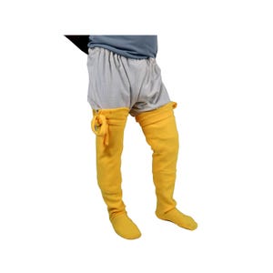 May include: A pair of yellow fabric leg warmers with a tie at the top. The leg warmers are worn over a pair of grey linen shorts.