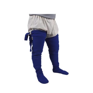 May include: Blue medieval-style leg warmers with a white linen undergarment. The leg warmers are tied at the top with a white cord and have a metal hook and eye closure.