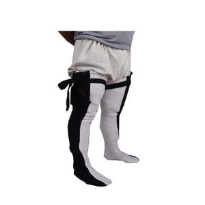 May include: White and black striped stockings with a black fabric strap and buckle at the top of each thigh. The stockings are worn by a person with a white linen undergarment.