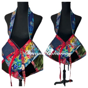May include: A patchwork shoulder bag featuring a vibrant mix of blue, red, yellow, and green fabric panels with paisley and floral patterns. The bag includes a long strap, tie closures, and the text Dream Bohemian printed across the front surface.
