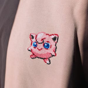 May include: A set of three ceramic mugs with a speckled, matte finish. The mugs are in shades of cream, light gray, and dark gray. Each mug has a simple, minimalist design and a rounded handle.