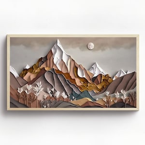 Könnte beinhalten: Ein Papierkunst-Druck einer Bergkette mit einem Vollmond am Himmel. Die Berge sind in Braun-, Beige- und Weißtönen geschichtet. Der Druck ist in einem hellen Holzrahmen gerahmt.
