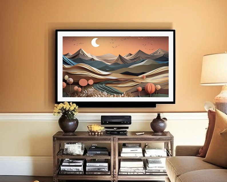 May include: A framed print of a paper art landscape featuring mountains, trees, and a crescent moon. The colours are muted and earthy, with shades of brown, green, and blue.