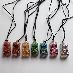 Op de afbeelding: Acht hars gummy bear kettingen in verschillende kleuren en met glitter. De kettingen zijn aan zwarte koorden.