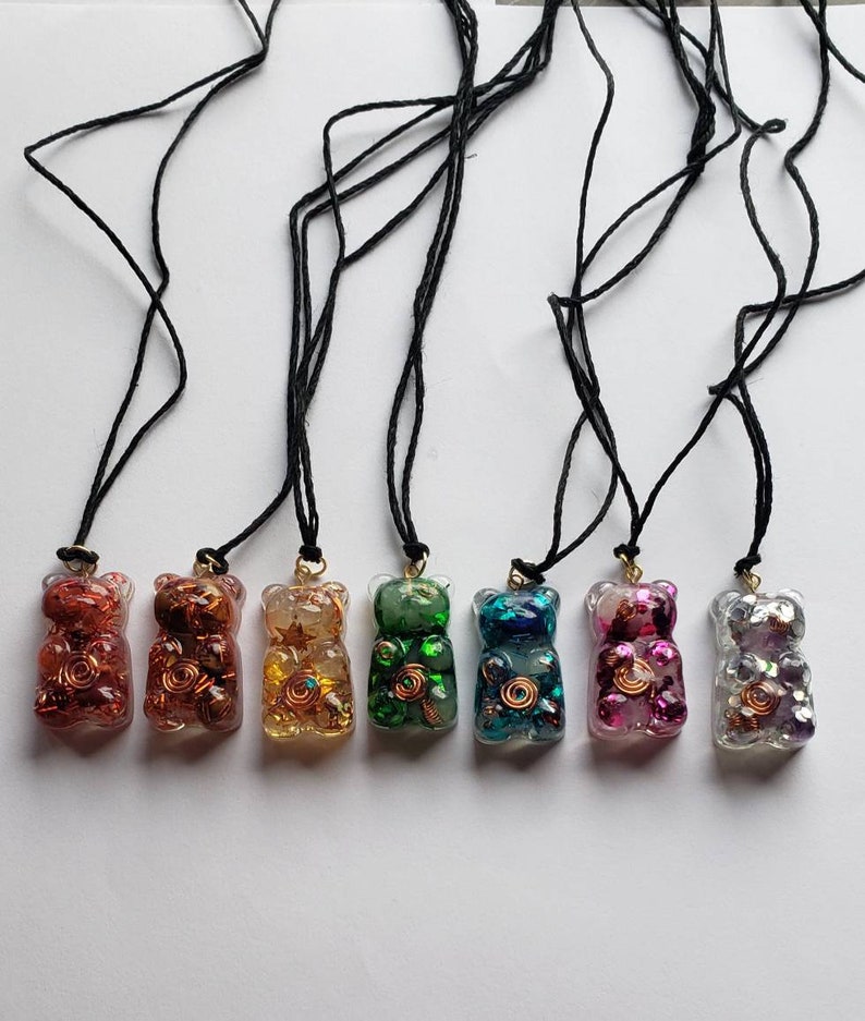 Op de afbeelding: Acht hars gummy bear kettingen in verschillende kleuren en met glitter. De kettingen zijn aan zwarte koorden.