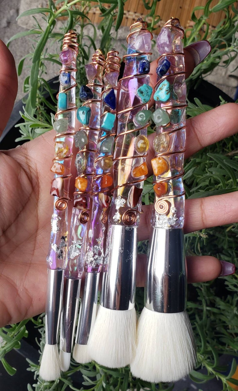 May include: Set of six makeup brushes with clear handles embedded with colourful gemstones and wrapped in copper wire. The brushes have silver metal ferrules and white bristles.