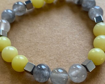 Op de afbeelding: Een armband gemaakt met lichtgrijze en gele kralen met zilveren metalen spacers.