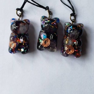 May include: Three black resin bear pendants with colorful glitter and copper wire accents. Each pendant is attached to a black cord.