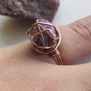 May include: A copper wire wrapped ring with a purple amethyst stone.