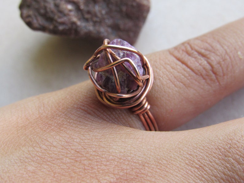 May include: A copper wire wrapped ring with a purple amethyst stone.