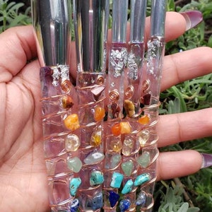 May include: Set of five makeup brushes with clear handles and colourful gemstone accents. The handles are wrapped with copper wire and feature various gemstones, including amethyst, turquoise, and citrine.