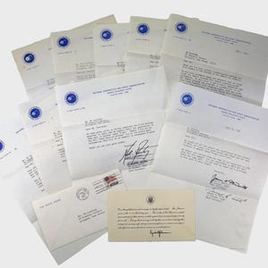 Puede incluir: Una colección de cartas y sobres antiguos, incluyendo correspondencia de la NASA y la Casa Blanca. Las cartas presentan membretes oficiales, firmas y sellos postales, lo que sugiere importancia histórica. El papel está envejecido.