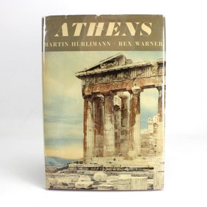 Pode incluir: Um livro vintage intitulado "Atenas" de Martin Hürlimann e Rex Warner. A capa apresenta uma fotografia do Parthenon, um templo histórico de Atenas, Grécia.