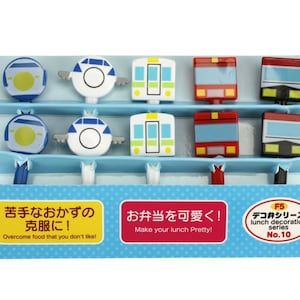 Puede incluir: Un conjunto de palillos de comida coloridos con forma de trenes y aviones, diseñados para decorar fiambreras. Los palillos se exhiben en un soporte azul escalonado con texto japonés.