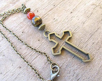 May include: A bronze-toned cross pendant necklace. The necklace features a chain with a lobster clasp, a cross-shaped pendant, and decorative beads in shades of red and brown. The cross is open-worked.