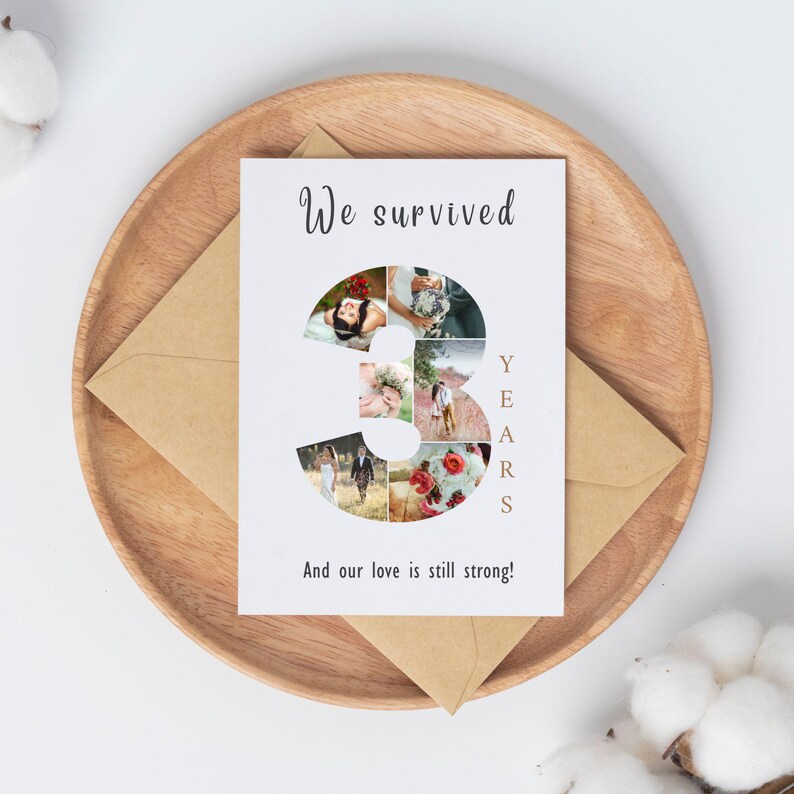 Pode incluir: Um cart&atilde;o branco com o texto "We survived" e "3 YEARS" num design estilizado. O n&uacute;mero 3 &eacute; preenchido com v&aacute;rias fotos pequenas. O cart&atilde;o est&aacute; numa bandeja de madeira com um envelope castanho.