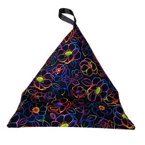 May include: A black triangular bean bag chair with a rainbow floral print. The chair has a black strap handle.
