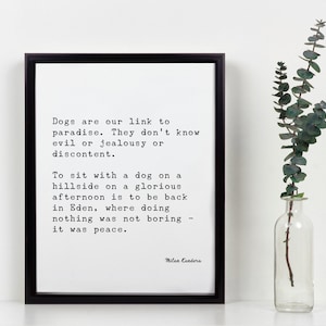 May include: Black and white typography print with a quote about dogs and paradise by Milan Kundera. The quote reads: "Dogs are our link to paradise. They don't know evil or jealousy or discontent. To sit with a dog on a hillside on a glorious afternoon is to be back in Eden, where doing nothing was not boring - it was peace."