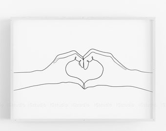 Op de afbeelding: Een minimalistische kunstprint met een doorlopende lijntekening van twee handen die een hartvorm vormen. Het kunstwerk is in zwart op een witte achtergrond, wat een eenvoudig ontwerp creëert. De lijst is wit.