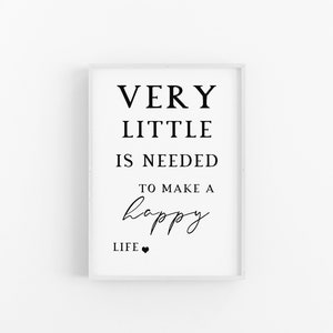 May include: A framed print with the text "VERY LITTLE IS NEEDED TO MAKE A happy LIFE." The words are in black, with the word "happy" in a cursive font. A small black heart is at the bottom. The frame is white.