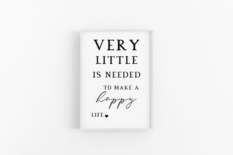 May include: A framed print with the text "VERY LITTLE IS NEEDED TO MAKE A happy LIFE." The words are in black, with the word "happy" in a cursive font. A small black heart is at the bottom. The frame is white.
