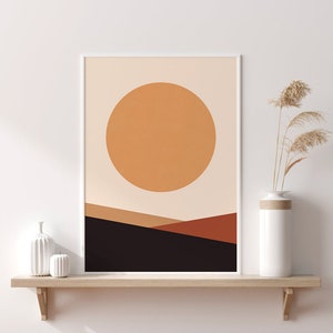 May include: Abstract art print featuring a large orange circle against a beige background, with layered brown and black shapes below. The artwork is framed in white and displayed on a wooden shelf with decorative vases.
