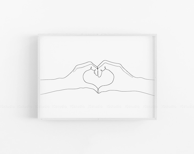 May include: A framed minimalist art print featuring a continuous line drawing of two hands forming a heart shape. The artwork is rendered in black against a white background, creating a simple yet impactful design. The frame is white.