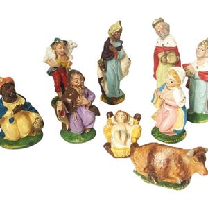 May include: A collection of nine hand-painted ceramic nativity figurines, including figures of the holy family, three kings, a shepherd with a lamb, and a cow. Each piece features vibrant colors and detailed facial expressions on a green base.