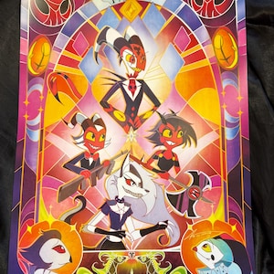 May include: A colorful poster featuring stylized cartoon characters in a stained-glass window design. The characters include demons and a wolf-like figure, with the letters "I.M.P." at the top. The artwork has a vibrant palette of reds, yellows, and purples.